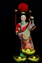 Chinese female doll in colourful costume with traditional gold ingots Royalty Free Stock Photo