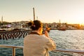 Chinese female tourist on a cruise ship taking photos of seascape at the Bosphorus strait and the sunset in Istanbul, vacation