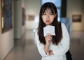 Chinese female visitor with guide-book looking at artwork painting