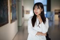 Chinese female visitor looking at artwork painting in the museum