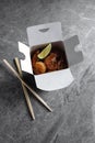 Chinese food in a black takeout box on a gray background. Sushi chopsticks and a black box Royalty Free Stock Photo