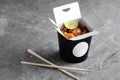 Chinese food in a black takeout box on a gray background. Sushi chopsticks and a black box Royalty Free Stock Photo