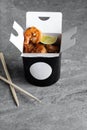 Chinese food in a black takeout box on a gray background. Sushi chopsticks and a black box Royalty Free Stock Photo