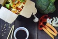 Chinese food, Noodles with pork and vegetables in take-out box on wooden table