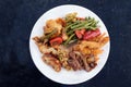 Chinese food, various meat and vegetables with fried rice and sauce on a white plate and a dark table with sparkling dots, copy