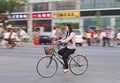 Chinese girl on a bicycle with shops on the background, Beijing, China