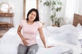 Chinese Girl Having Lower Abdominal Pain Sitting In Bed Indoors Royalty Free Stock Photo