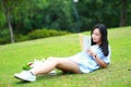 Chinese Girl reading the book. Blonde beautiful young woman with book lying on the grass. Royalty Free Stock Photo