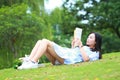 Chinese Girl reading the book. Blonde beautiful young woman with book lying on the grass. Royalty Free Stock Photo