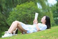 Chinese Girl reading the book. Blonde beautiful young woman with book lying on the grass. Royalty Free Stock Photo