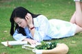 Chinese Girl reading the book. Blonde beautiful young woman with book lying on the grass. Royalty Free Stock Photo