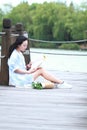 Chinese Girl reading book. Blonde beautiful young woman with book sit on bridge near fence. Royalty Free Stock Photo