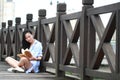 Chinese Girl reading book. Blonde beautiful young woman with book stand near fence. Royalty Free Stock Photo