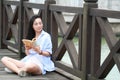 Chinese Girl reading book. Blonde beautiful young woman with book stand near fence. Royalty Free Stock Photo