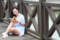 Chinese Girl reading book. Blonde beautiful young woman with book stand near fence. Royalty Free Stock Photo