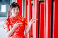 Chinese girl in traditional Chinese cheongsam pointing at china temple and introduce something to you