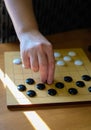Hands of woman playing Asian board game. Chinese go game board, close up view of playing black and white stone pieces