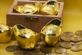 Chinese Gold Ingots and coins in treasure chest on yellow background.
