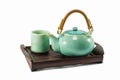 Chinese green teapot and teacups on the wooden trivet