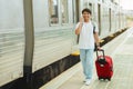 Chinese guy tourist walking by train station, talking on phone Royalty Free Stock Photo