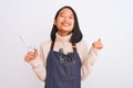 Chinese hairdresser woman wearing apron holding scissors over isolated white background screaming proud and celebrating victory Royalty Free Stock Photo