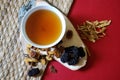 Bowl of chinese herb tea with pieces of astragalus and huang qi roots and jujubes on red background. Top view. Royalty Free Stock Photo