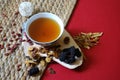 Bowl of chinese herb tea with pieces of astragalus and huang qi roots and jujubes on red background. Top view. Royalty Free Stock Photo