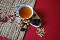 Bowl of chinese herb tea with pieces of astragalus and huang qi roots and jujubes on red background. Top view. Royalty Free Stock Photo