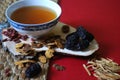 Goji berries, chinese dates, astragalus root pieces with a bowl of herb tea on red background. Side view. Royalty Free Stock Photo