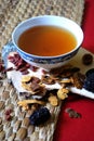 Goji berries, chinese dates, astragalus root pieces with a bowl of herb tea on red background. Side view. Royalty Free Stock Photo