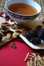 Goji berries, chinese dates, astragalus root pieces with a bowl of herb tea on red background. Side view. Royalty Free Stock Photo