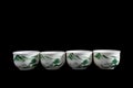 Chinese / Japanese Traditional Four White Tea Cup Set with Green Tree Scene Pattern in Solid Black Background Royalty Free Stock Photo