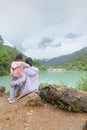 Chinese kid leaning against moms shoulder by beautiful lake