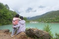 Chinese kid leaning against moms shoulder by beautiful lake