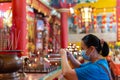 Chinese Lady with medical face mask pray with holding smoking incense sticks at Chinese Temple