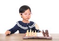 Chinese little girl with glasses frame playing chess seriously Royalty Free Stock Photo