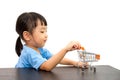 Chinese little girl pushing a toy shopping cart Royalty Free Stock Photo