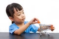 Chinese little girl pushing a toy shopping cart Royalty Free Stock Photo