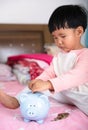 Chinese little girl is putting euro coins into piggy bank Royalty Free Stock Photo
