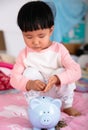 Chinese little girl is putting euro coins into piggy bank Royalty Free Stock Photo