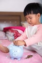 Chinese little girl is putting euro coins into piggy bank Royalty Free Stock Photo