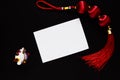 Chinese lucky knot, maneki neko cat figurine and empty paper card on black Royalty Free Stock Photo