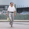 Chinese male senior walks on a zebra crossing, Shanghai, China