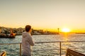 Chinese male tourist on a cruise ship enjoying the view of seascape at the Bosphorus strait and the sunset in Istanbul, vacation