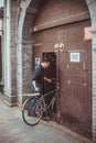 Chinese man with a bicycle enters old brown wooden gates