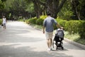 Chinese man people pushing cart and baby on the road in garden at public park in Shantou or Swatow city in Guangdong, China