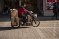 Chinese man riding a cargo moped loaded with goods wrapped in cardboard in a street in China. Cargo bikes or freight mopeds are po