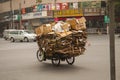 Chinese man riding a cargo tricycle loaded with cardboard waste on a road in China. Cargo bikes or freight tricycles are popular t