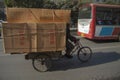 Chinese man riding a cargo tricycle loaded with goods wrapped in cardboard in a street in China. Cargo bikes or freight tricycles
