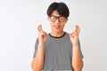 Chinese man wearing glasses and navy striped t-shirt standing over isolated white background gesturing finger crossed smiling with Royalty Free Stock Photo